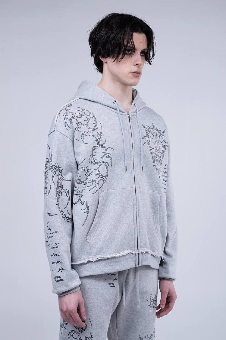 Angled front view of the heather gray Sigil Zip Hoodie with raw-edge hem and sleeve prints