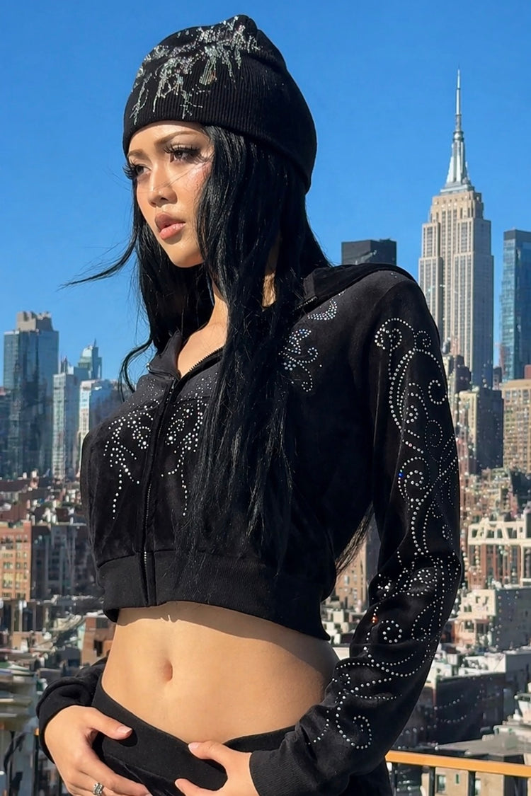 Long-haired model in the Velour Flutter Hoodie on a city rooftop with skyline behind