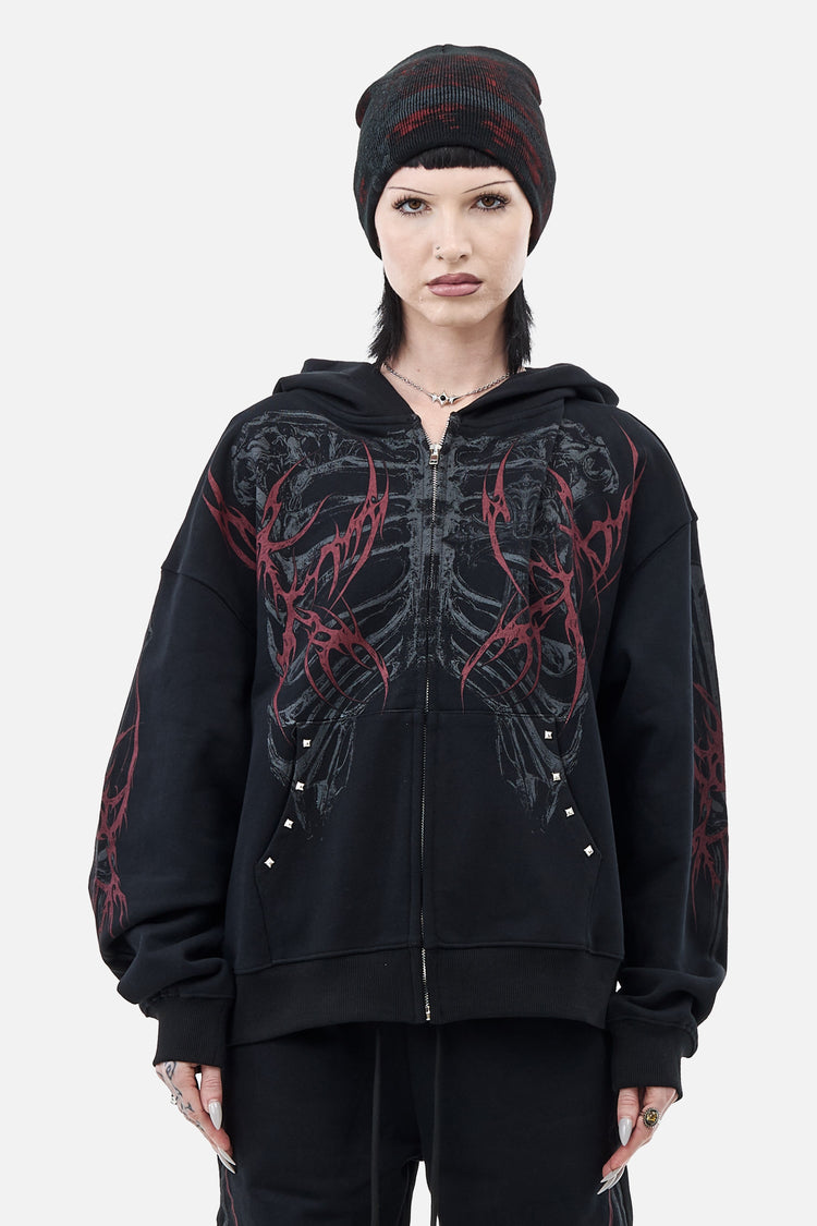 Model in a beanie wearing the black Skeleton Hoodie with grey ribcage and red thorn print