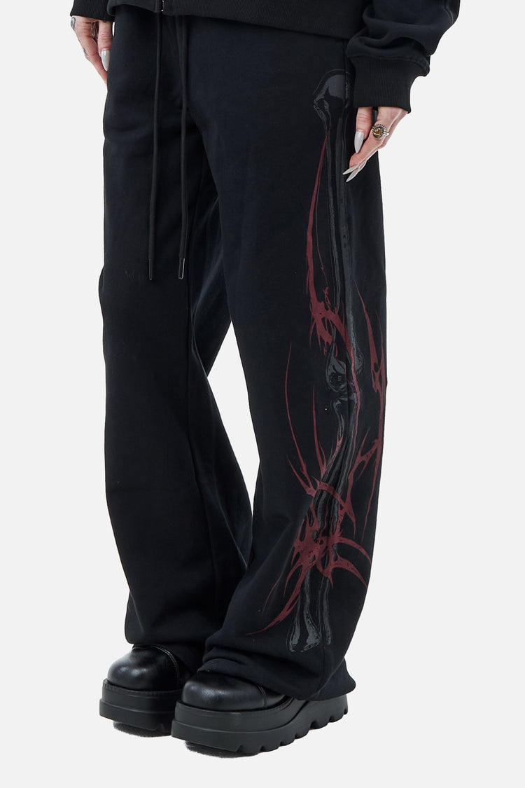 Close view of the Skeleton Sweatpants leg showing red tribal and gray spine graphic