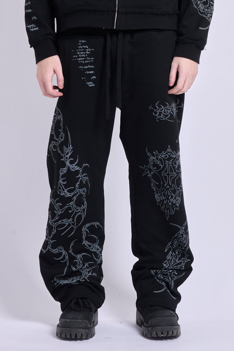 Front close-up of the Sigil Sweatpants showing the drawstring waist and silver tribal embroidery