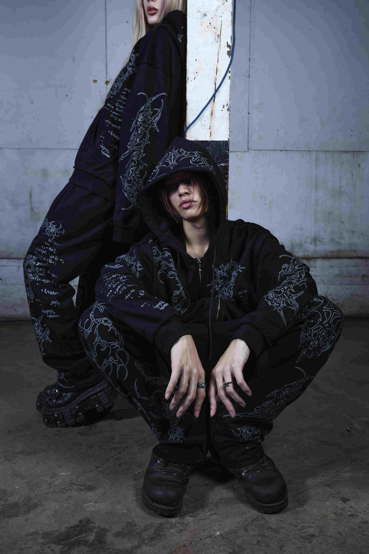 Two models in the Sigil sweatsuit posing in a concrete industrial space