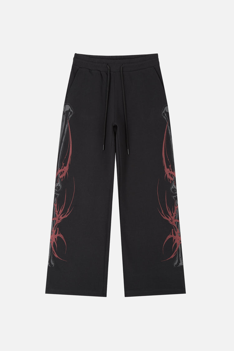 Front of the black Skeleton Sweatpants laid flat with red tribal spine prints on both legs