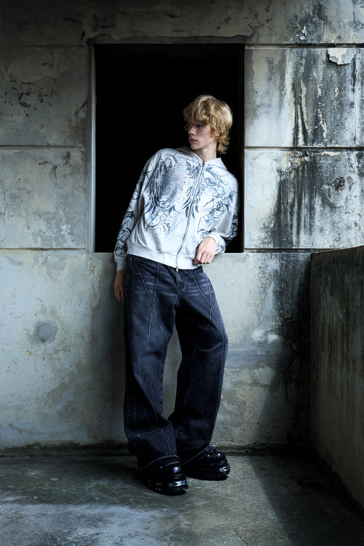Model in a white graphic jacket and black Vex Denim leaning in a concrete doorway