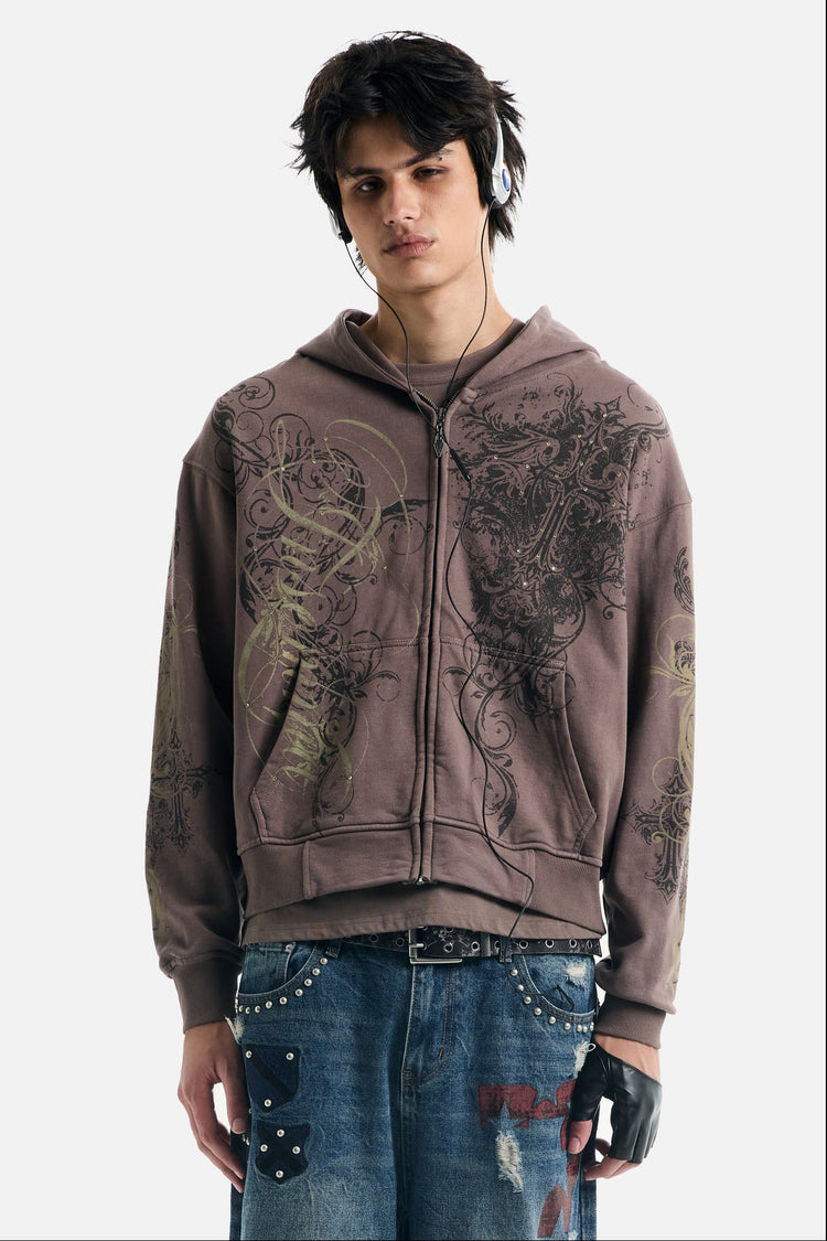 Model wearing the Brown Scripture Eclipse Zip Up Hoodie with ornate scroll and cross print