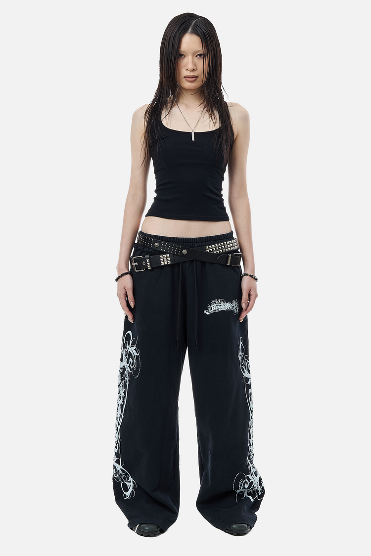 Model wearing the black Eternal Sweatpants with a cropped black tank and studded belts, front view