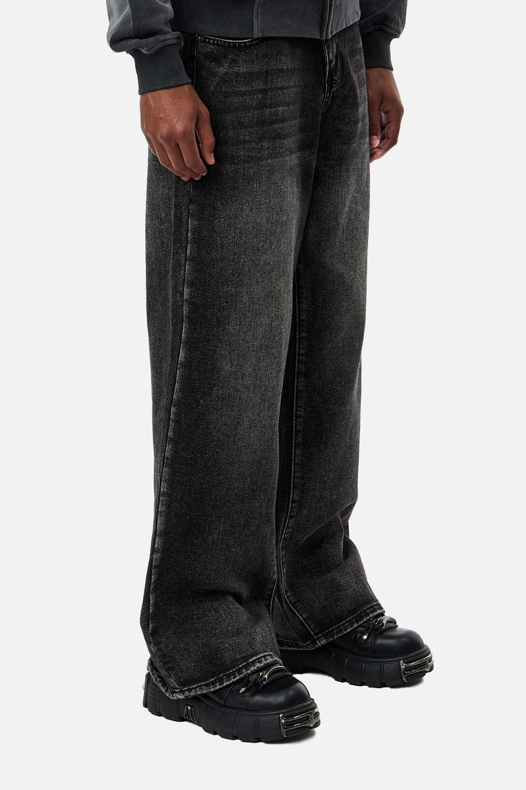 Angled view of the wide-leg Washed Black Outlaw Denim with stacked hems over chunky shoes