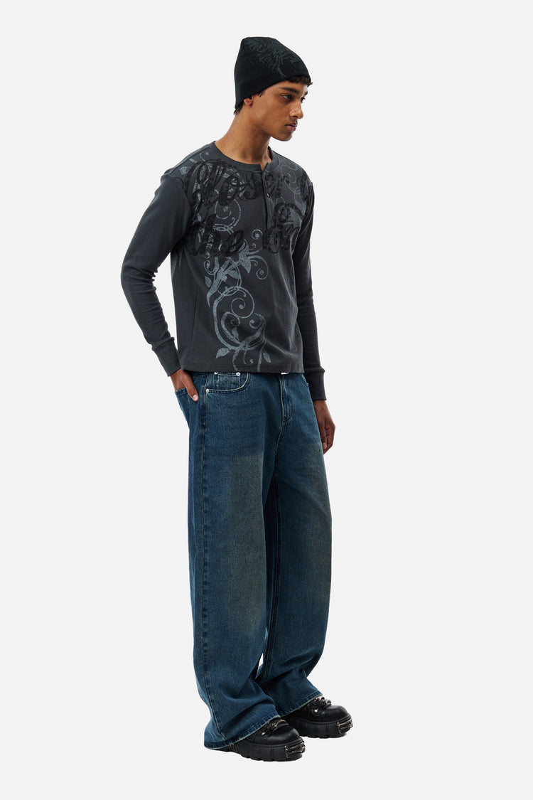 Full-length side view of the Washed Blue Outlaw Denim with a grey graphic long sleeve