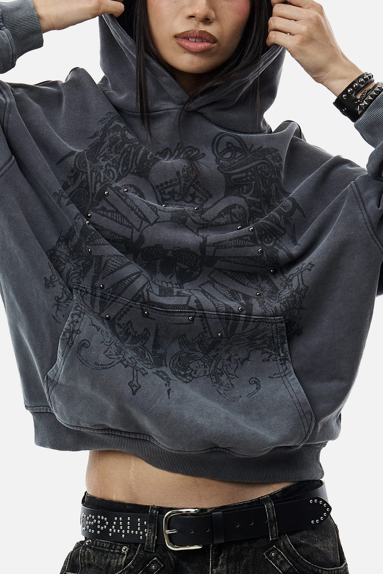 Model holding up the hood of the Crest Hoodie, cropped close-up of the front print
