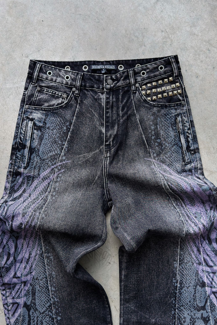 Close view of the Snakeskin Tribal Destroyer Denim on concrete, showing the studded pocket and snakeskin print