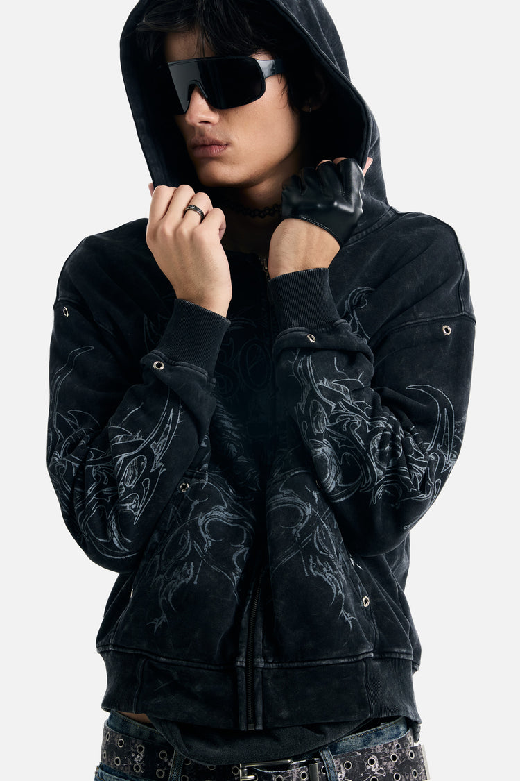 Model holding the raised hood of the Tribal Zip Up Hoodie, tribal sleeve print visible