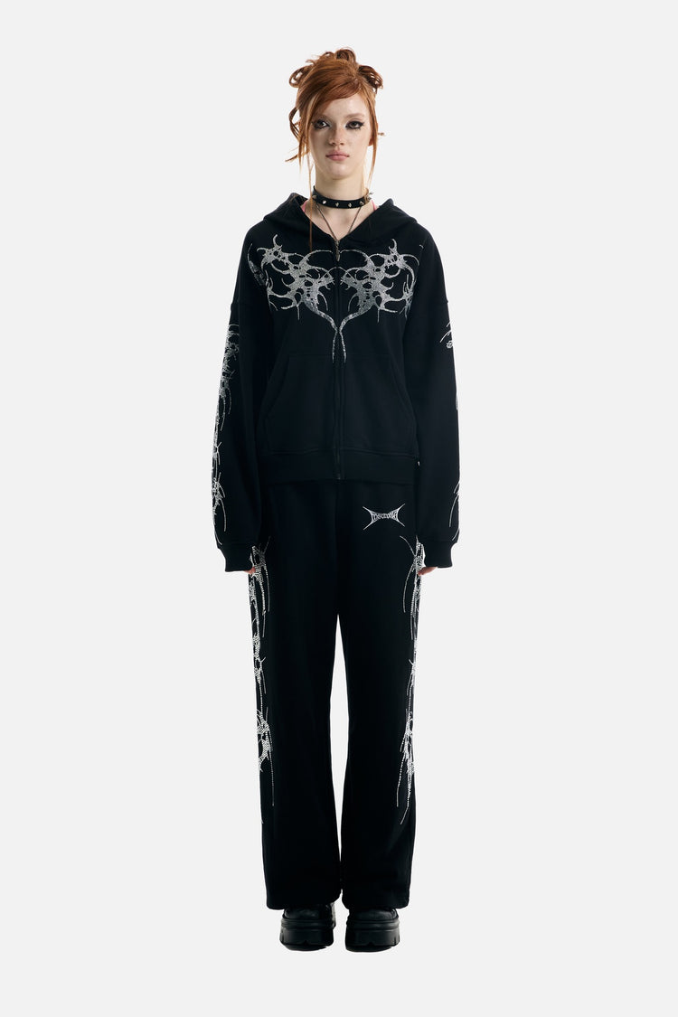 Model wearing the Thorns Rhinestone Sweatpants with the matching zip hoodie, full-length front view