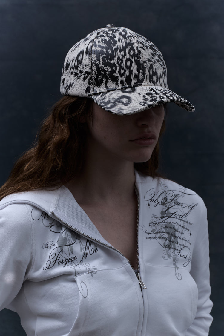 Long-haired model in the White Cheetah Cap with a white script zip hoodie