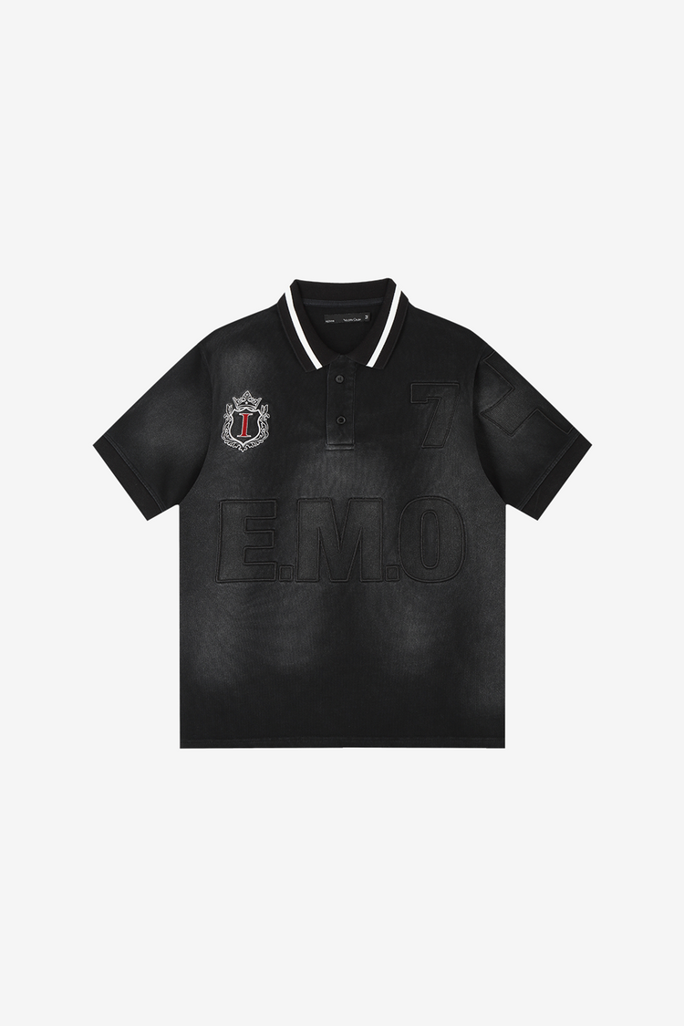 Front of the faded black E.M.O Polo laid flat, with striped collar and crest patch