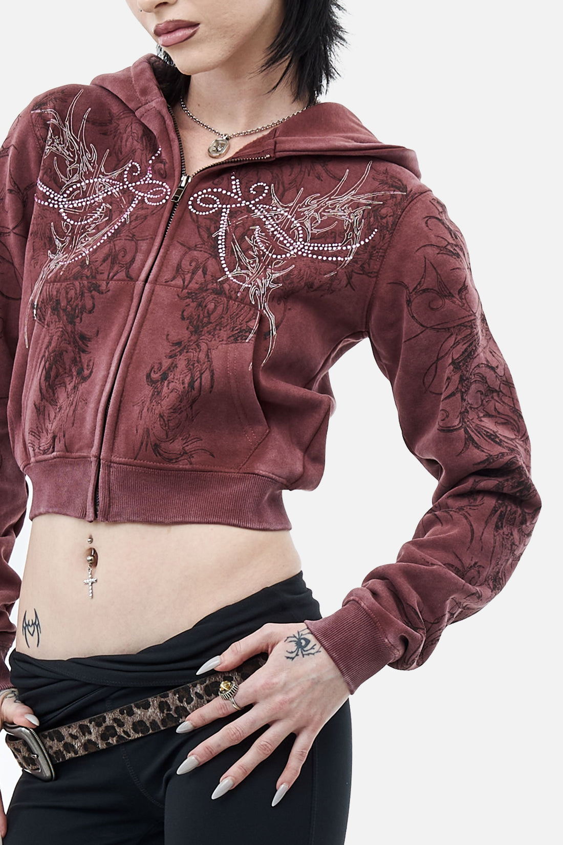 Close-up of the Fever Hoodie front showing rhinestone wings and tonal scroll print