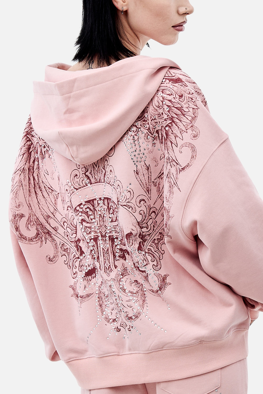 Over-the-shoulder back view of the pink Bonnie Hoodie showing the burgundy wing print