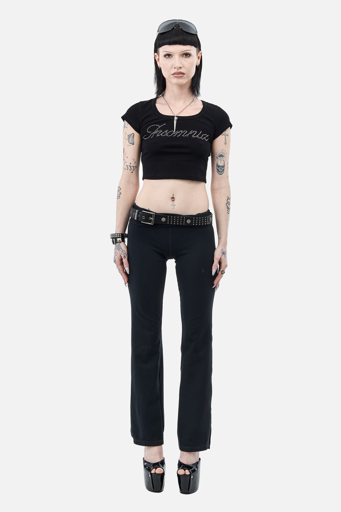 Full-length view of the Rhinestone Cursive Tee styled with black flares and platform heels