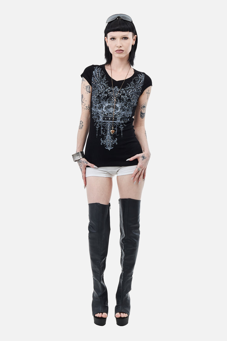 Full-length view of the Shrine Tee styled with white shorts and black thigh-high boots
