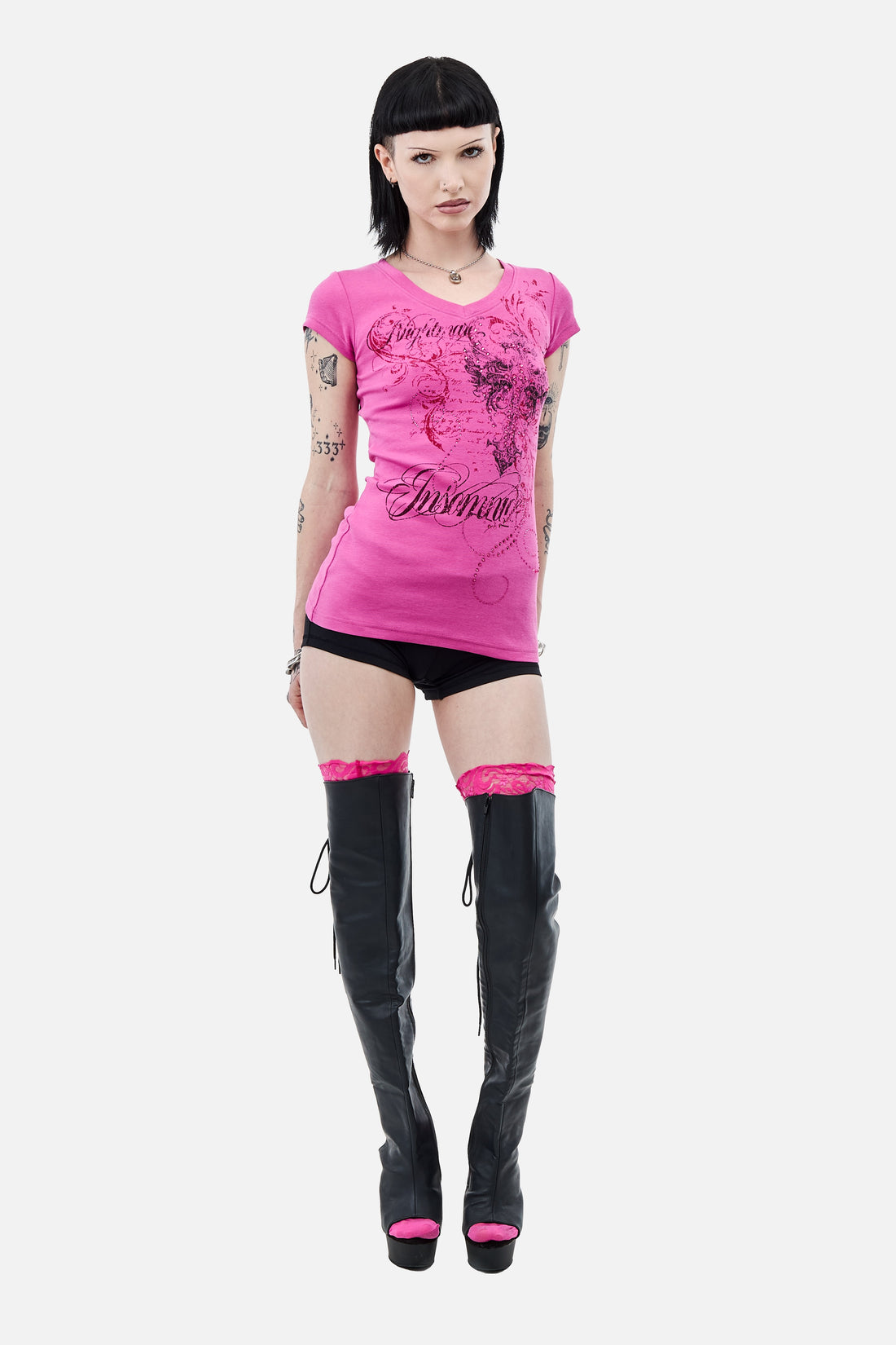 Model wearing the pink Lovers V-Neck T-Shirt with black shorts and thigh-high boots, full-length