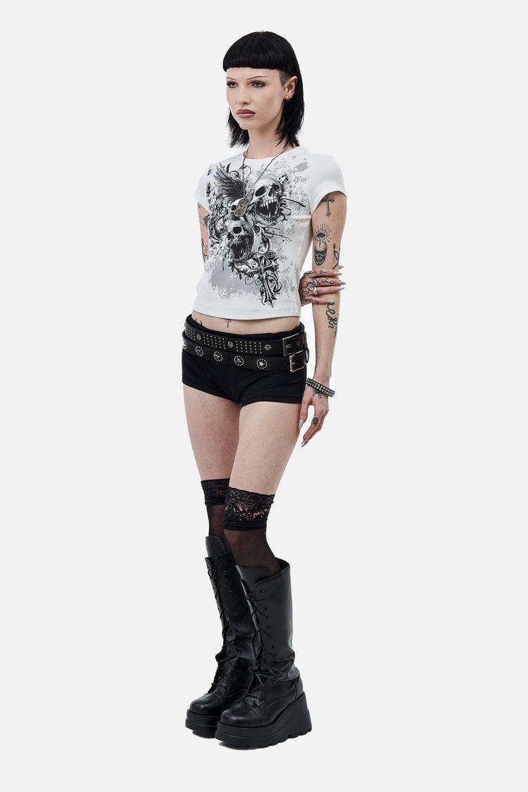 Full-length side pose in the white Skulls Tee with black shorts and platform boots
