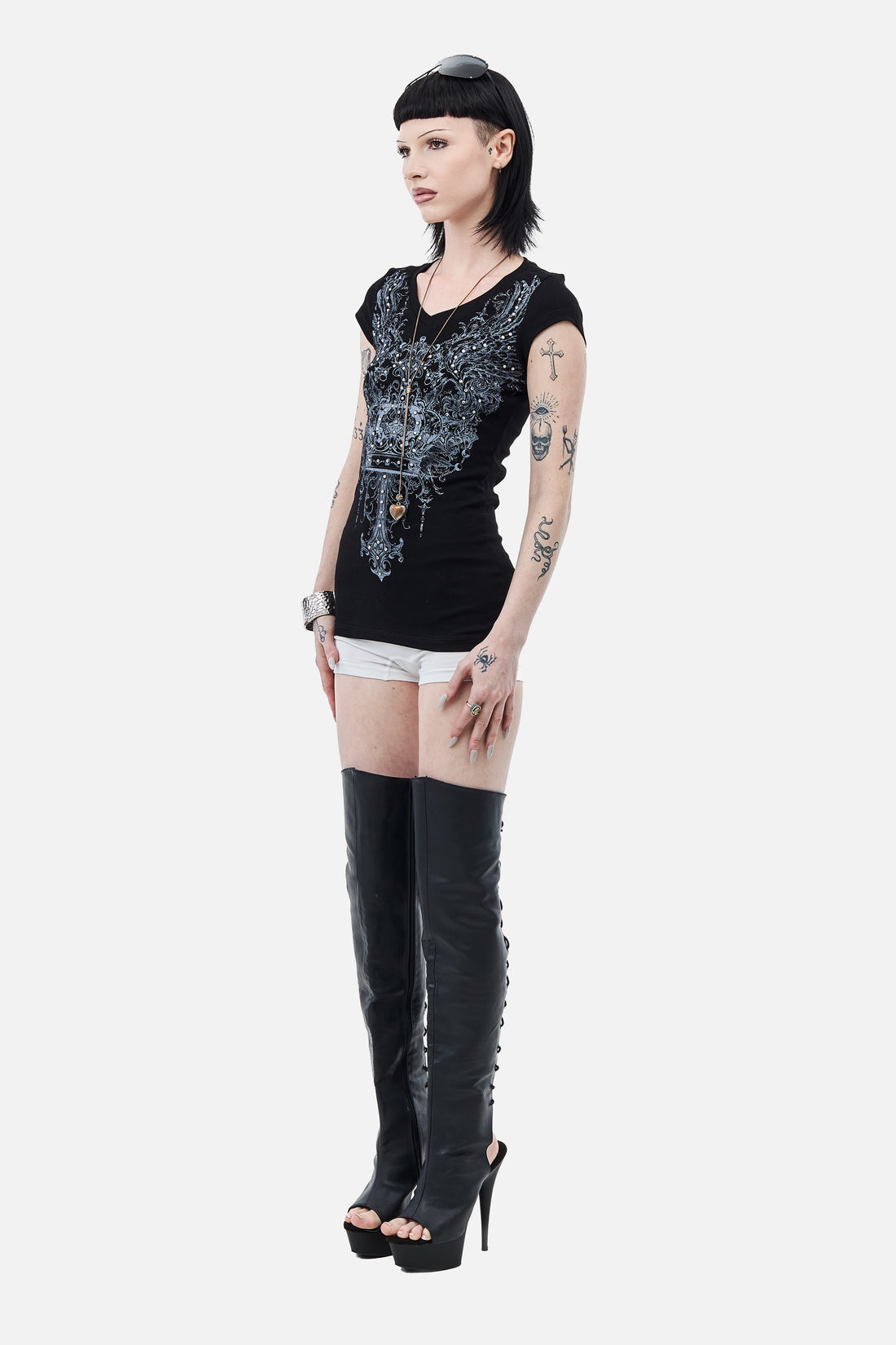 Side view of the fitted black Shrine Tee with white shorts and thigh-high boots