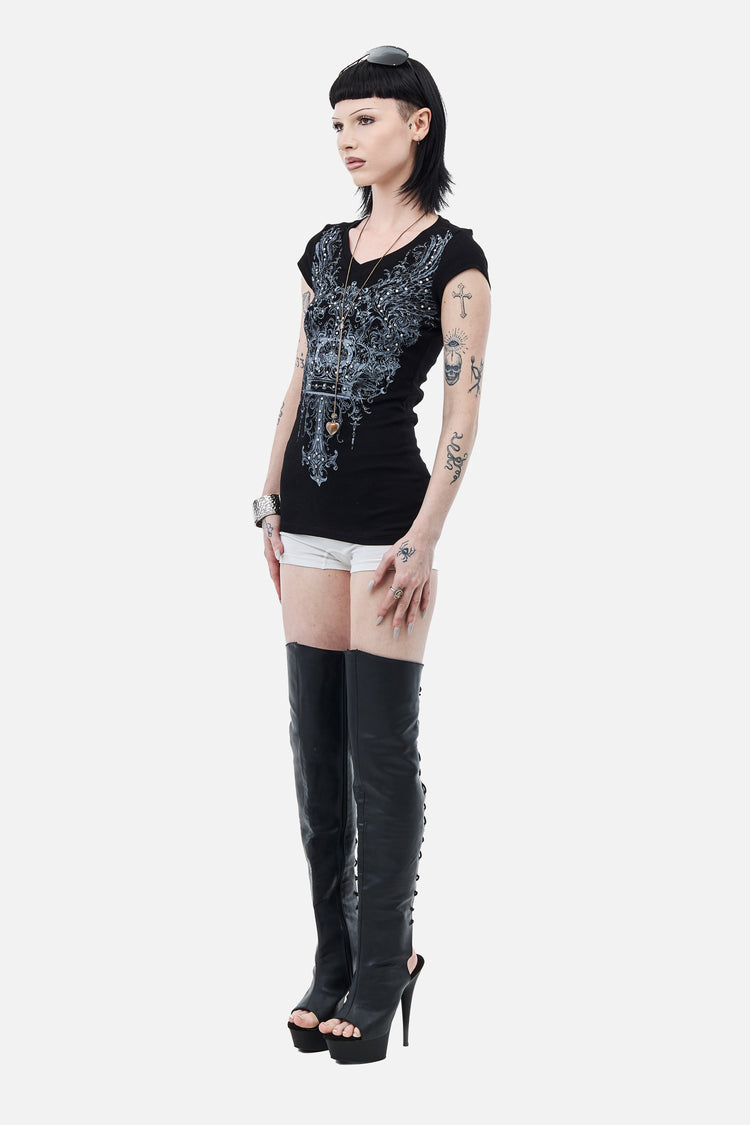 Side view of the fitted black Shrine Tee with white shorts and thigh-high boots