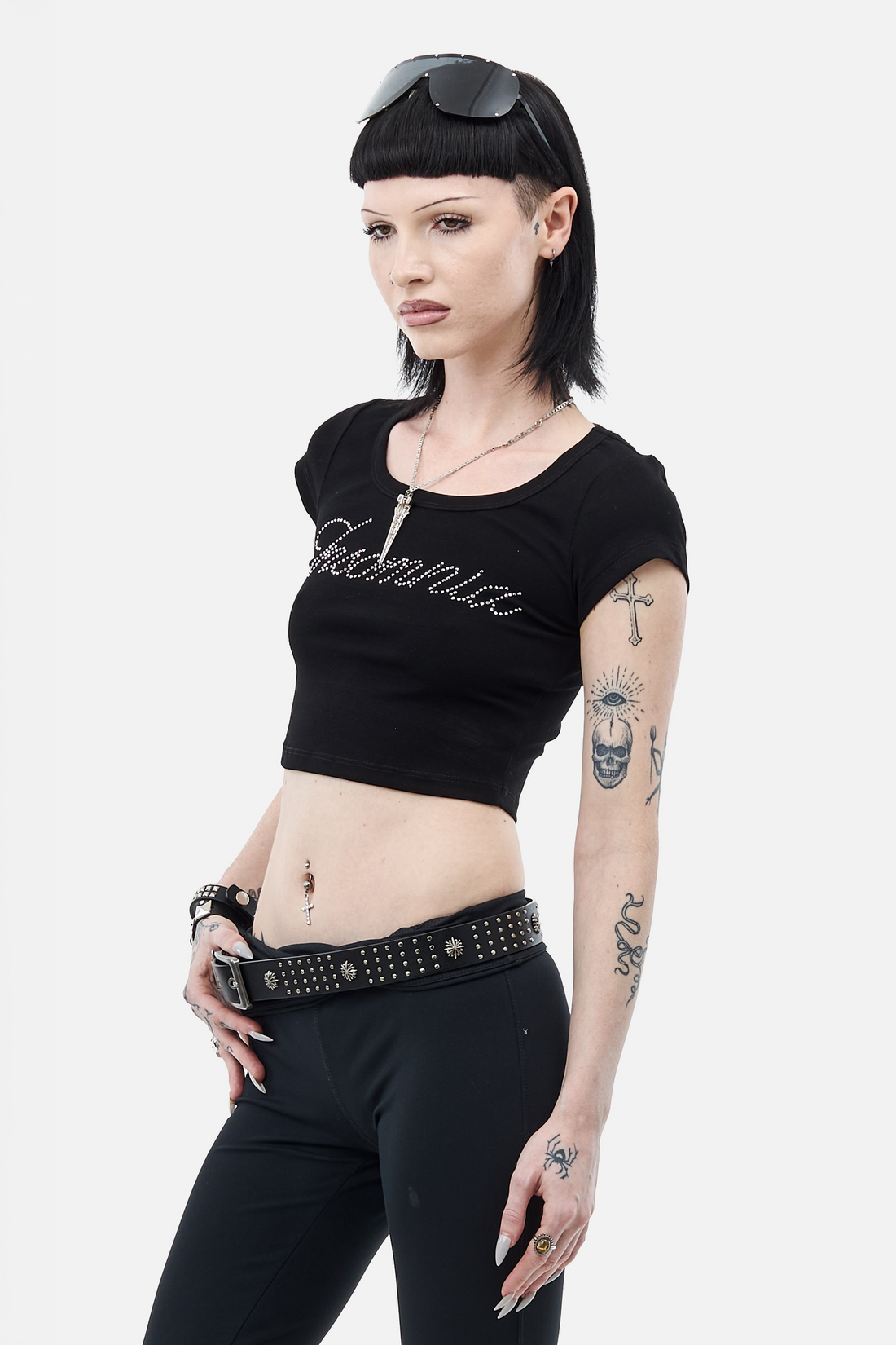 Model wearing the cropped black Rhinestone Cursive Tee with a studded belt, three-quarter view