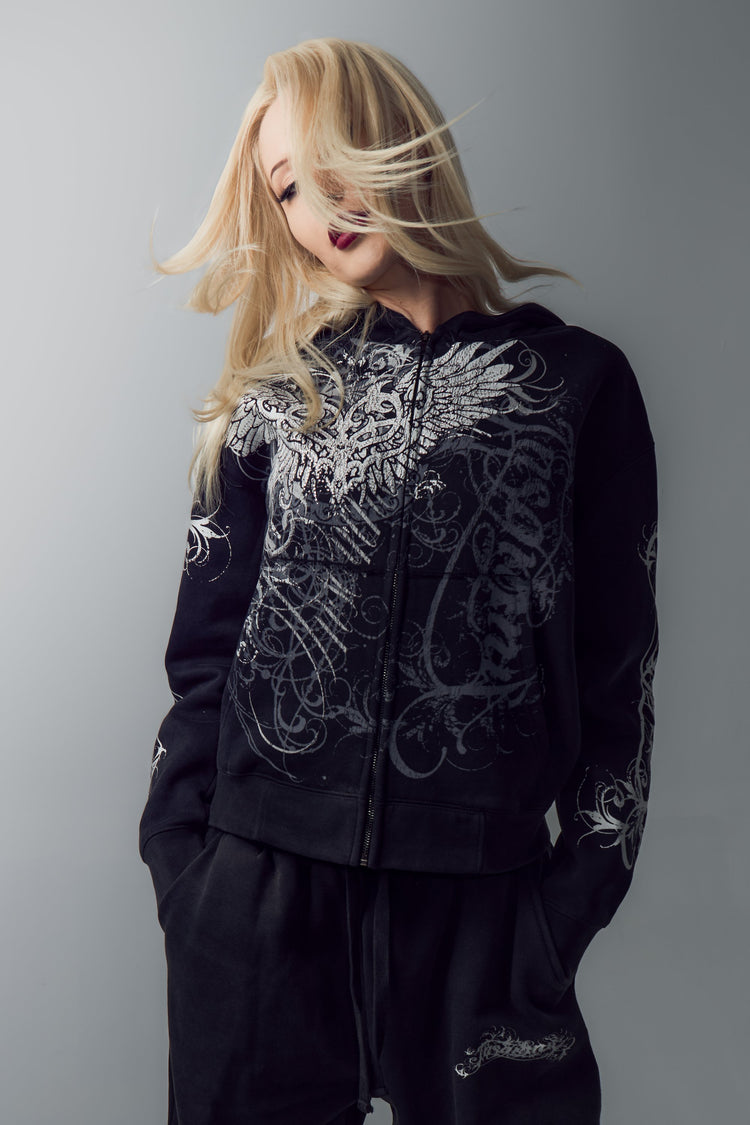 Blonde model in the Eternal Zip Hoodie with hair in motion, grey studio backdrop