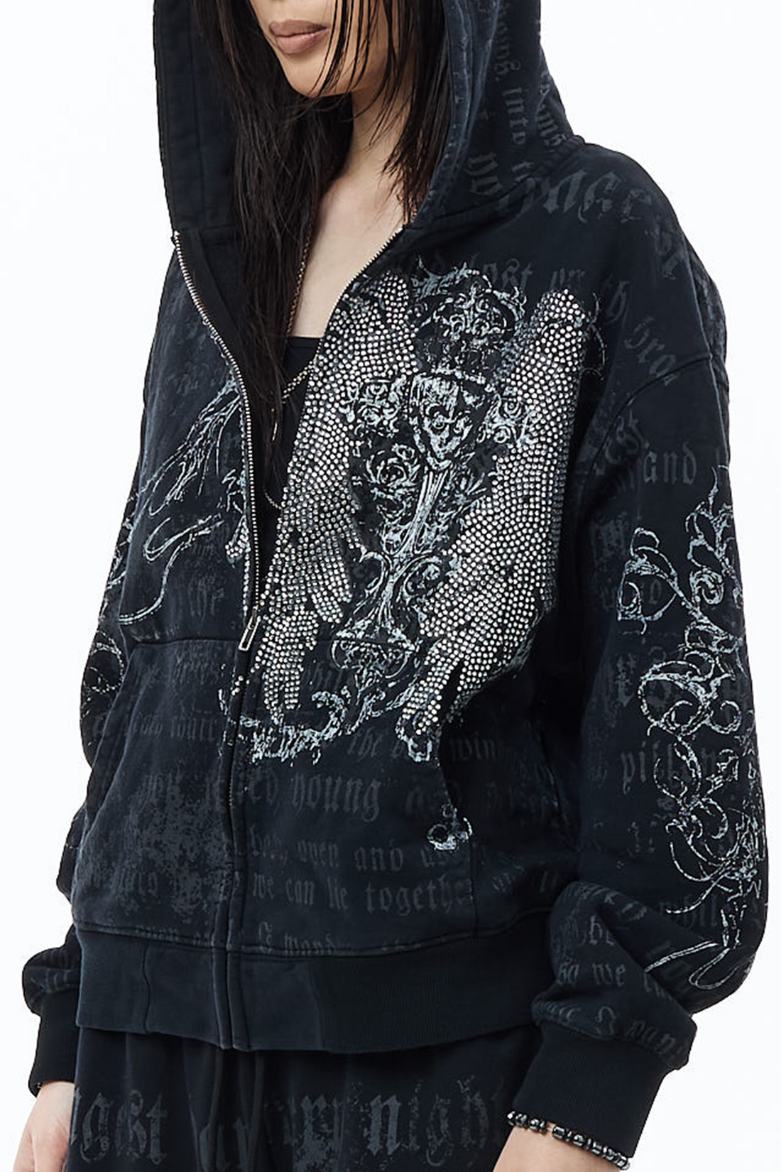 Close-up of the Sacred Zip Hoodie front showing the rhinestone winged cross design