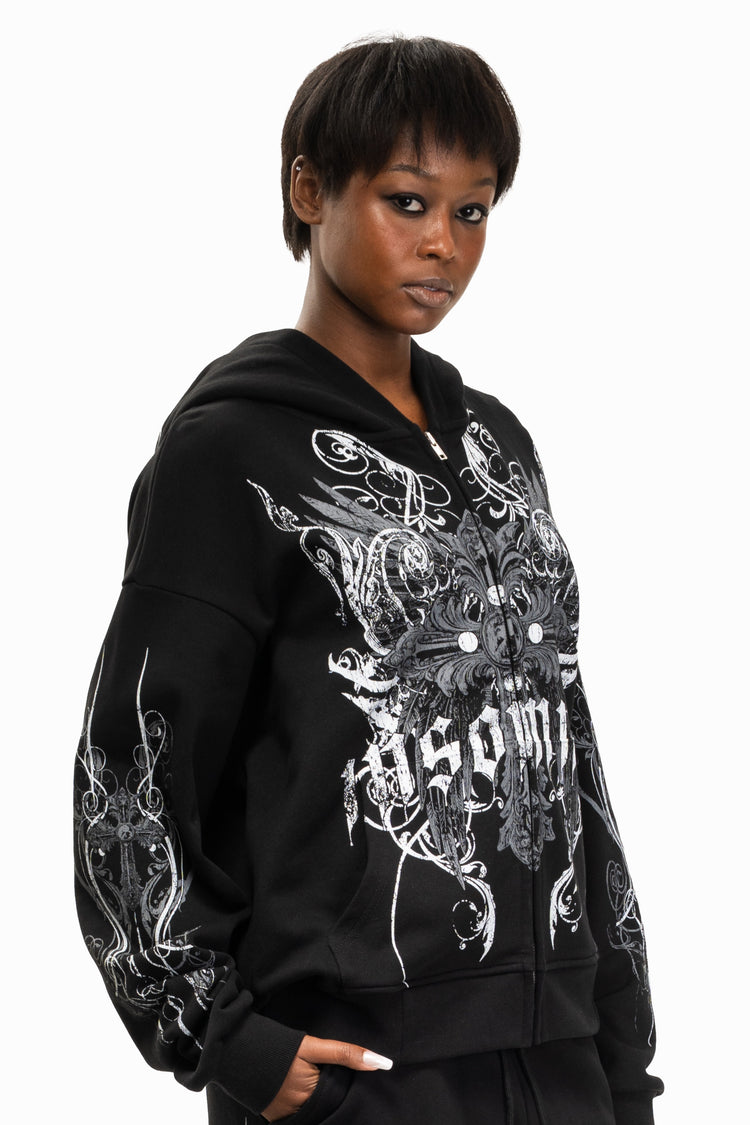 Model in the black Crux Hoodie with hood down, three-quarter view of the print