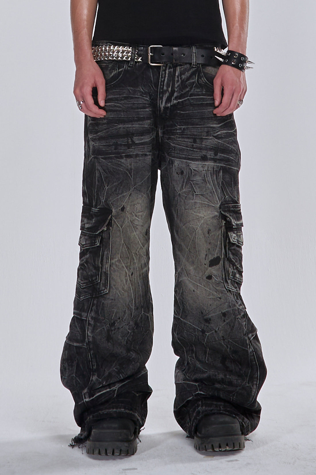 Waist-down view of the Fractured Denim cargo jeans with a studded belt and black shoes