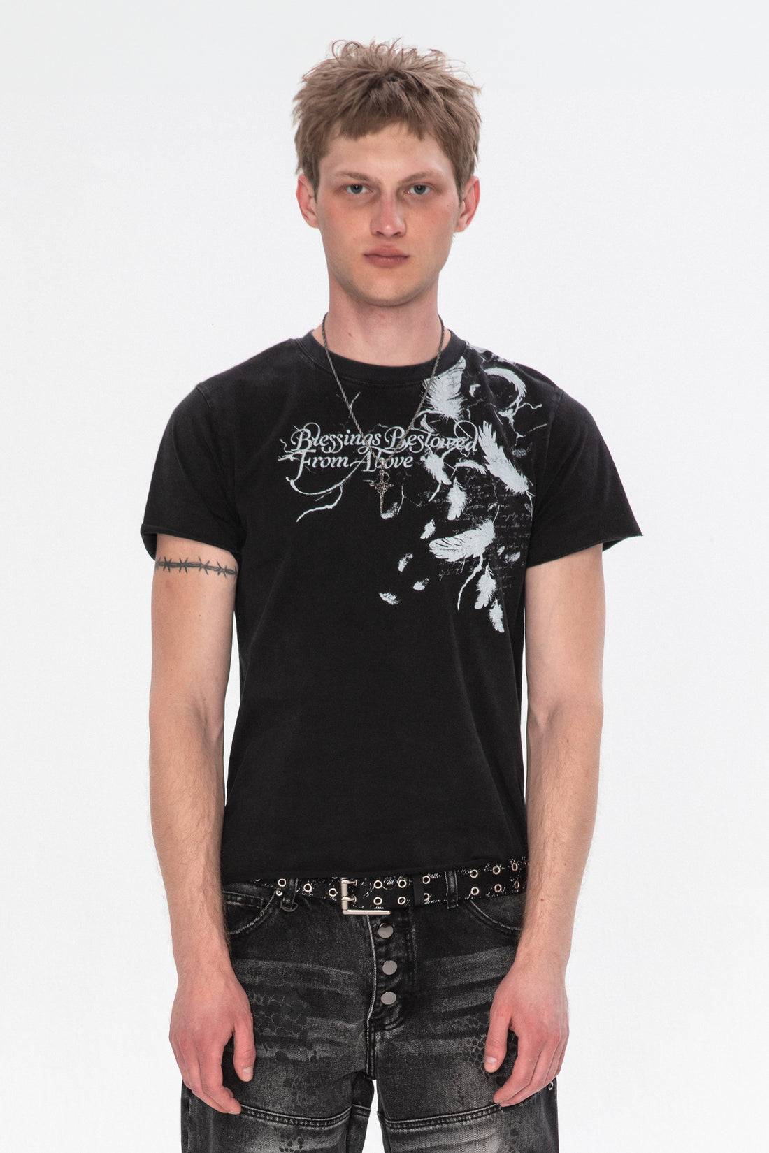 Model wearing the Black Feather Tee with white feather and script print over one shoulder, front view