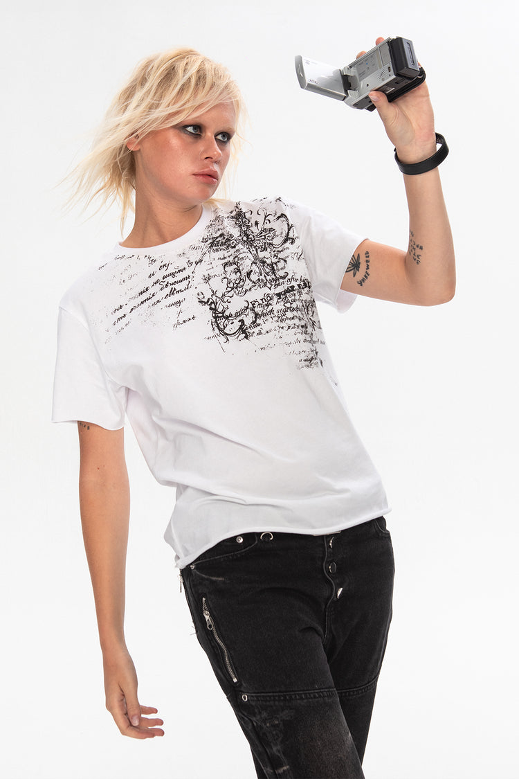 Blonde model holding a camcorder in the white Orison Tee with black script graphic