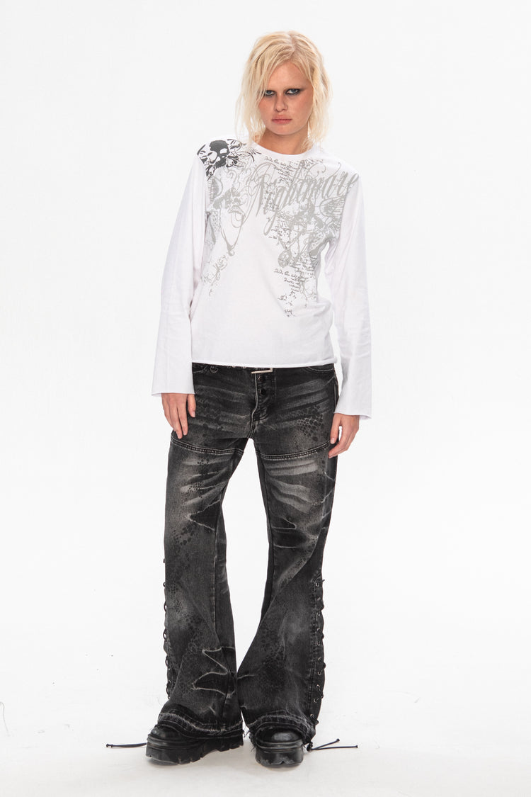 Full-length view of the Snakeskin Flared Denim styled with a white long-sleeve graphic tee