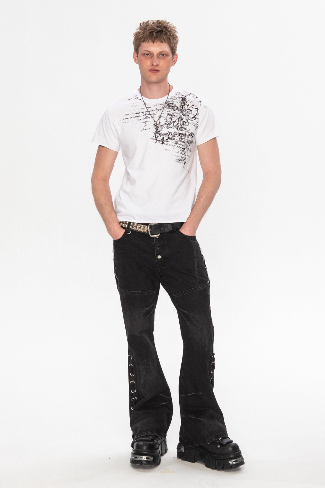 Full-length view of the white Orison Tee worn with black flared jeans and boots