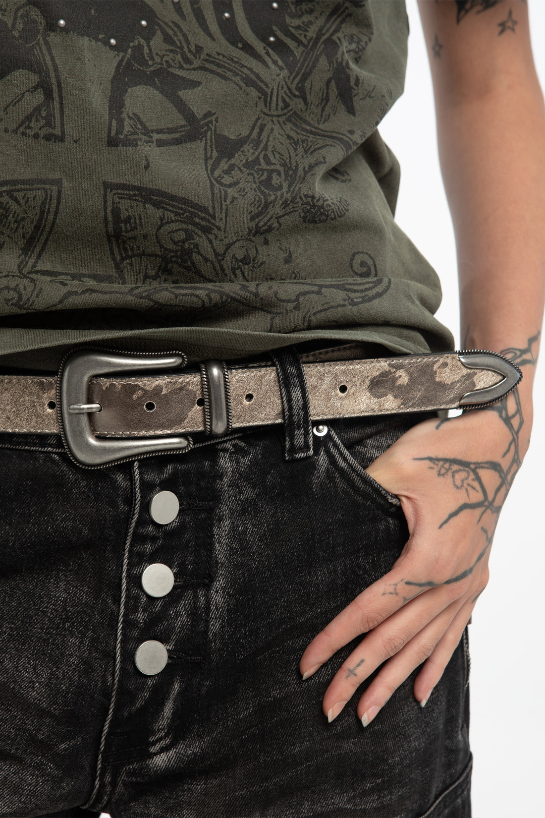 Close-up of the Stallion Belt on black button-fly jeans with tattooed hand in pocket