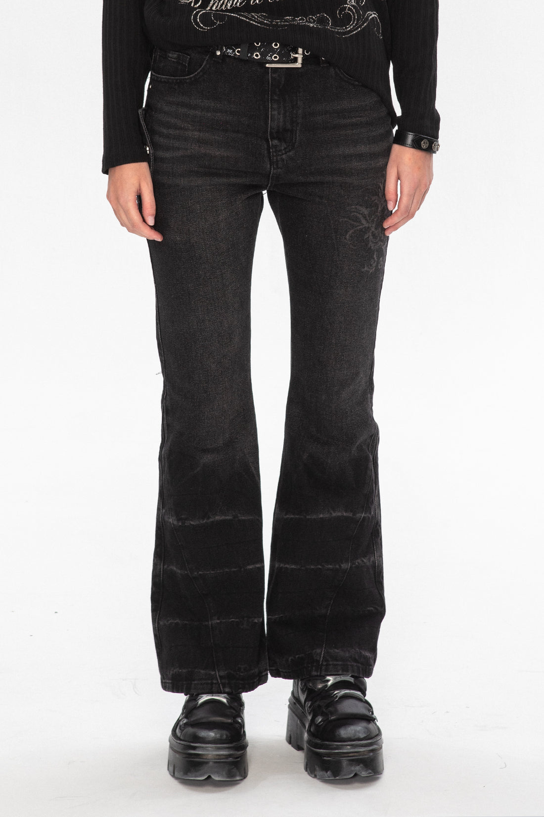 Front view of the faded black Thorns Flared Denim with black platform boots