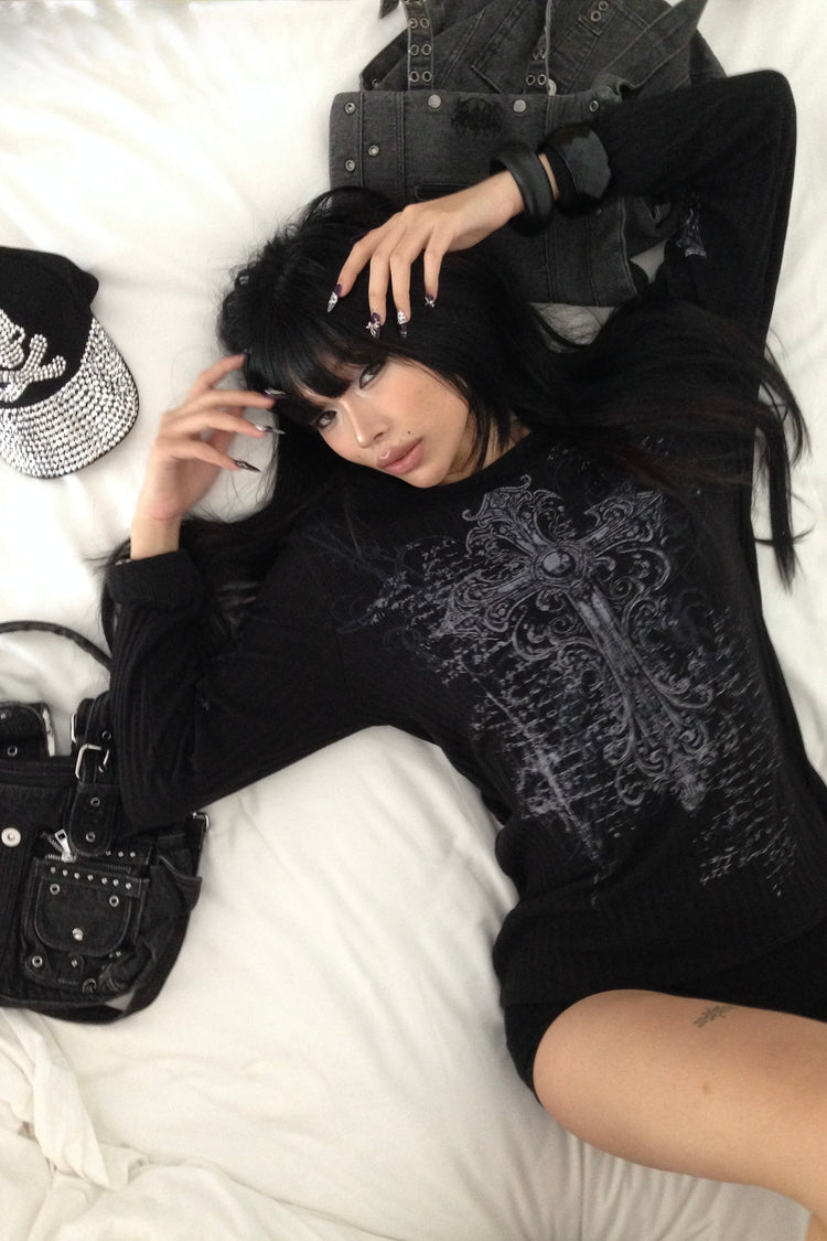 Model lying on white sheets wearing the black Scripture Ribbed Long Sleeve