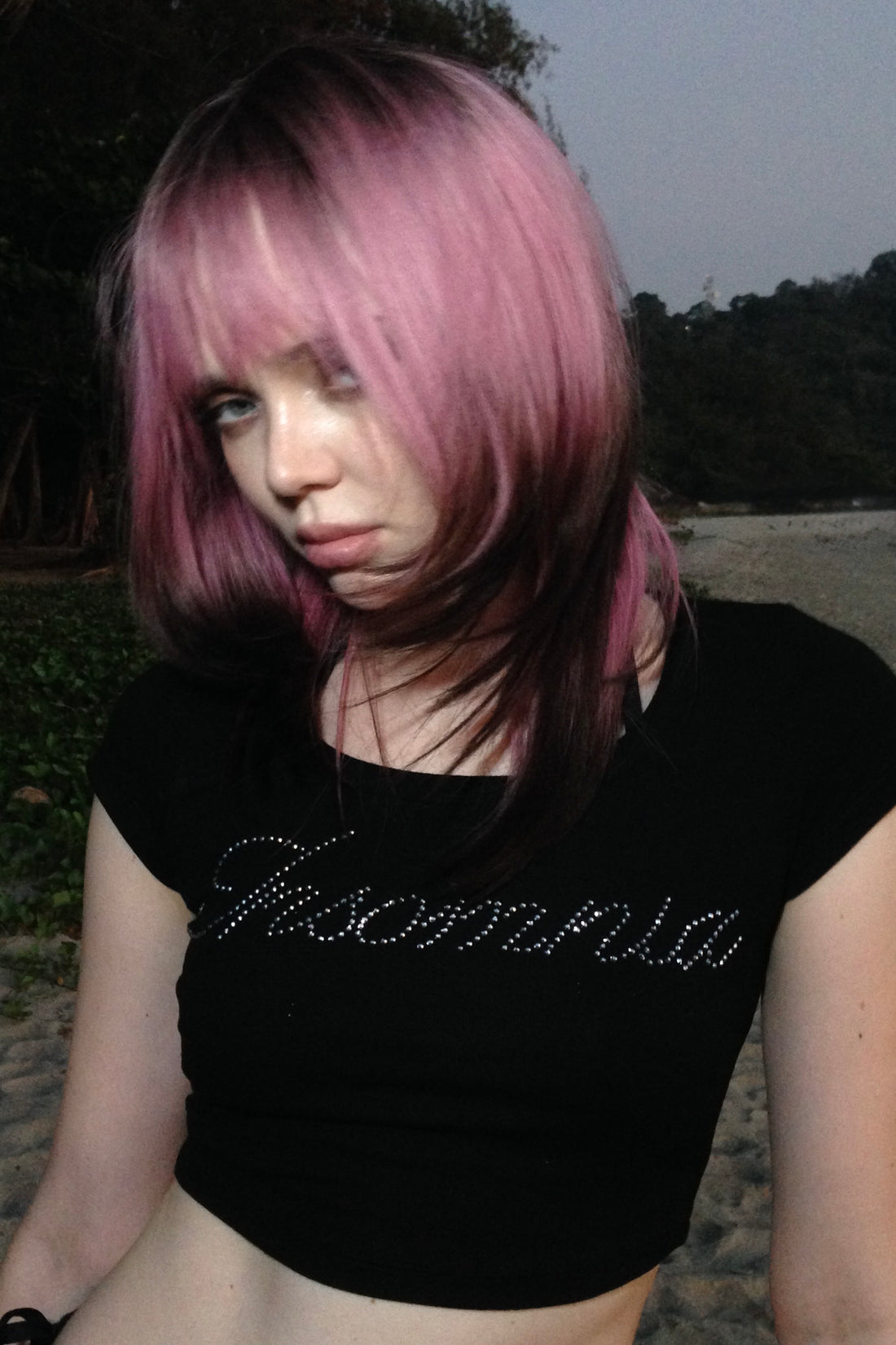 Pink-haired model outdoors wearing the black Rhinestone Cursive Tee with Insomnia script