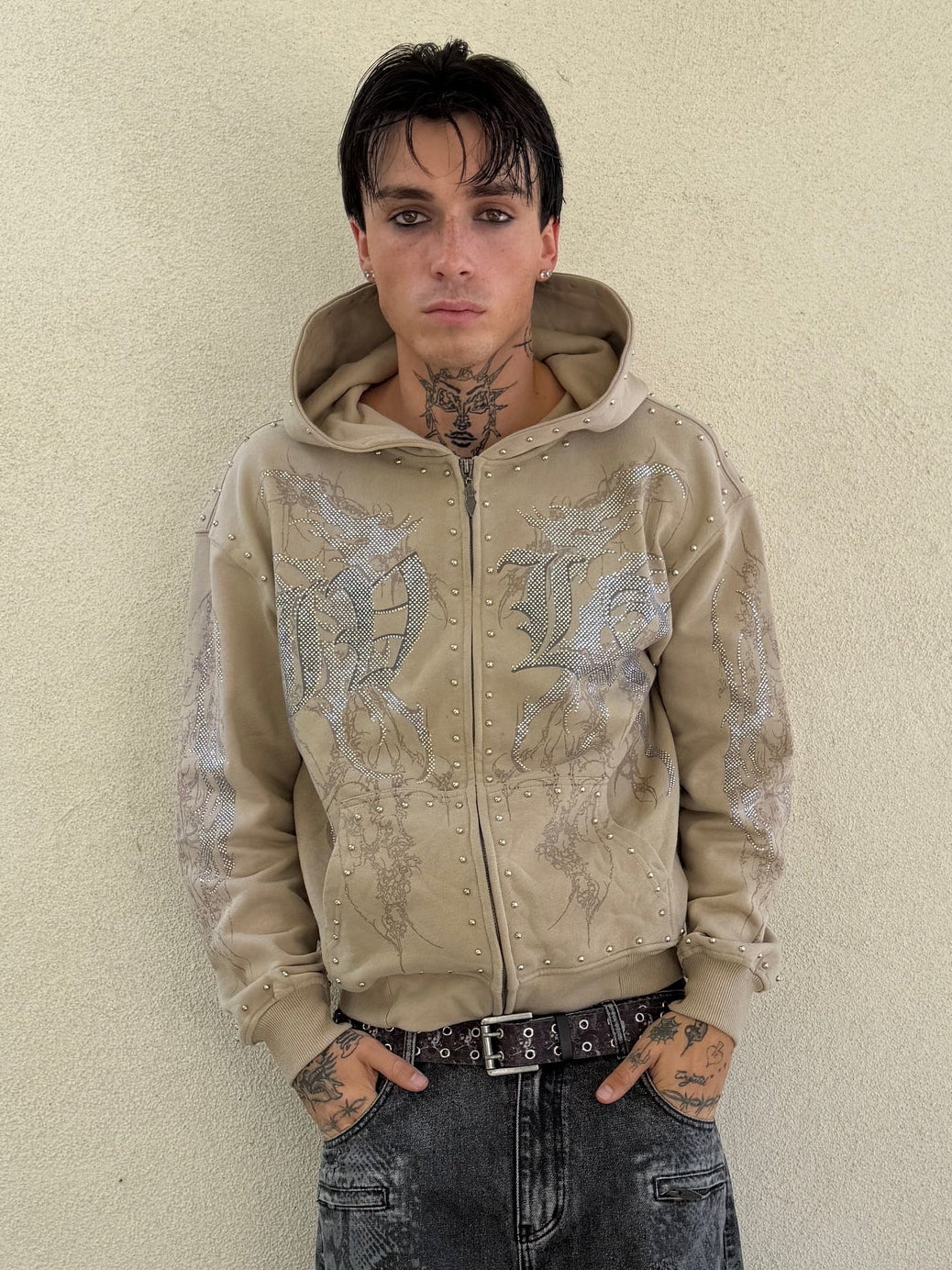 Front view of the IVLA Zip Up Hoodie on a tattooed model against a cream wall