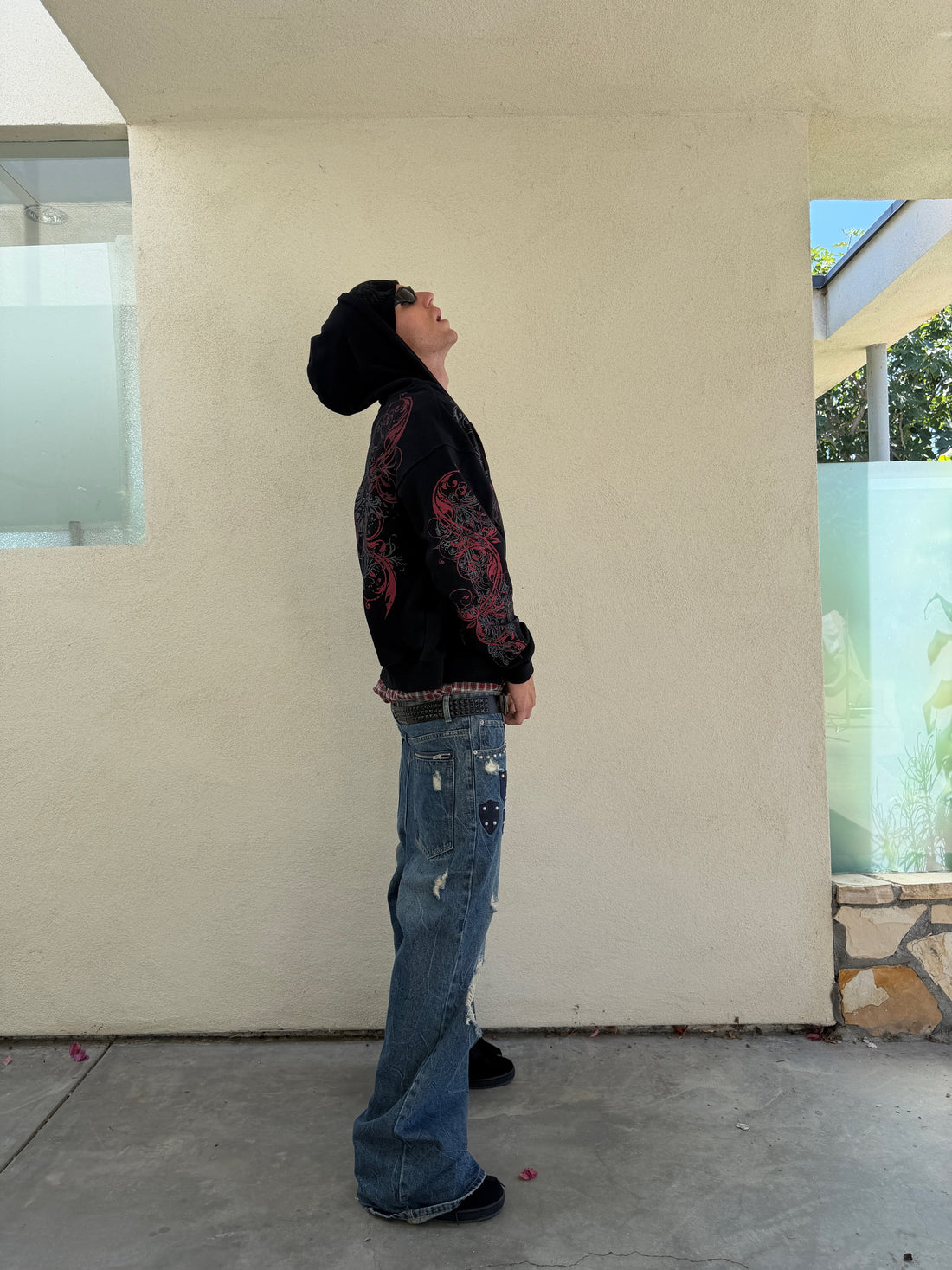 Side view of the Black Scripture Eclipse Zip Up Hoodie with baggy jeans, model looking up
