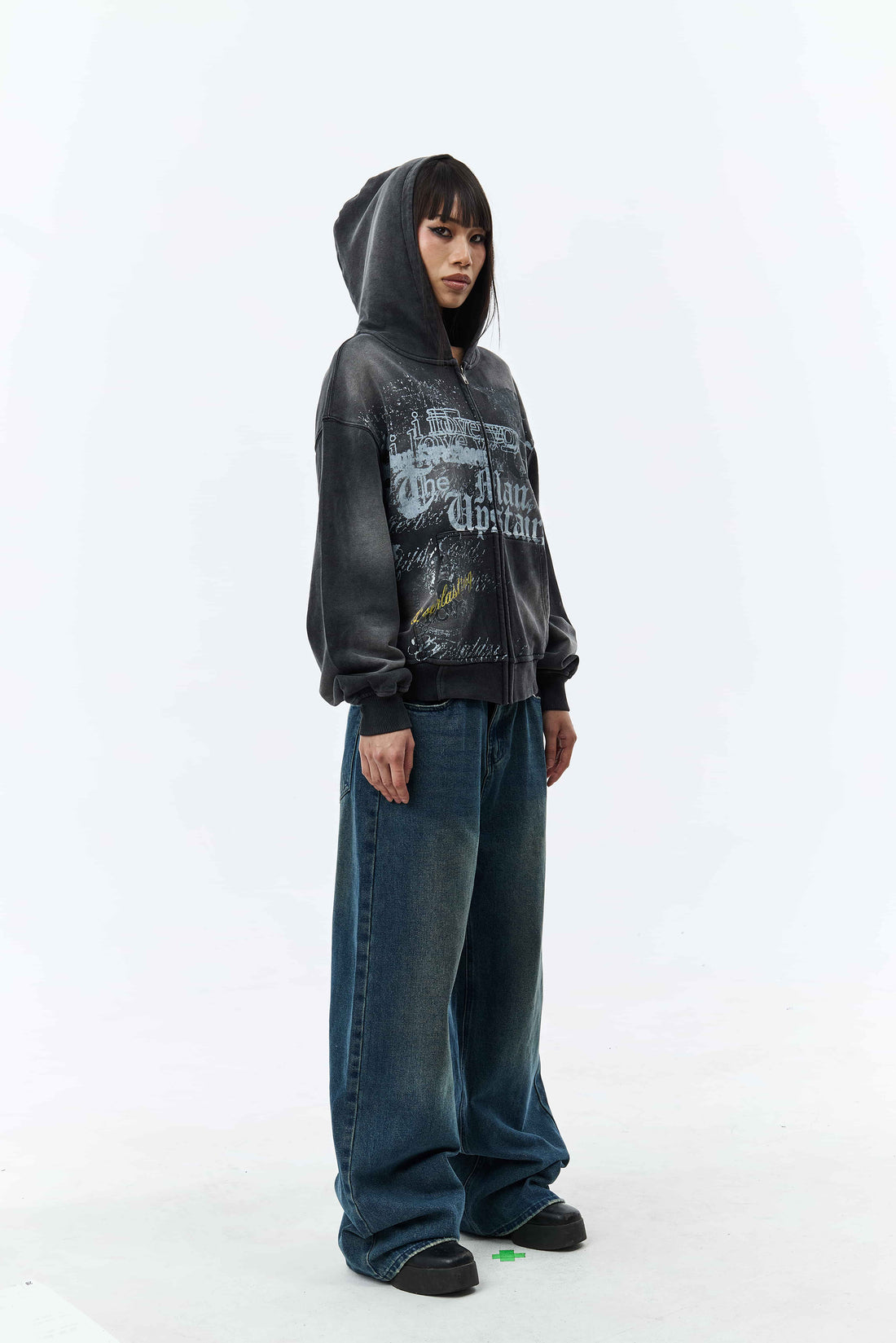 Model in the Upstairs Zip Hoodie with hood up and blue baggy jeans, three-quarter view
