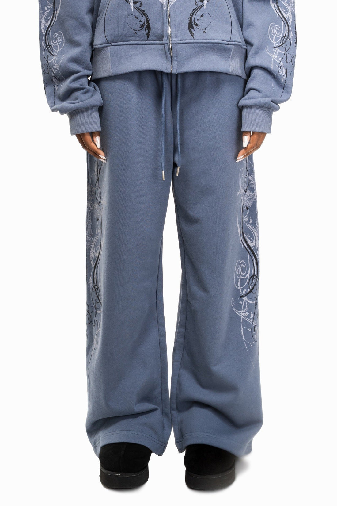 Close-up of the Midnight Blue Crux Sweatpants worn with matching hoodie, embroidery down the legs
