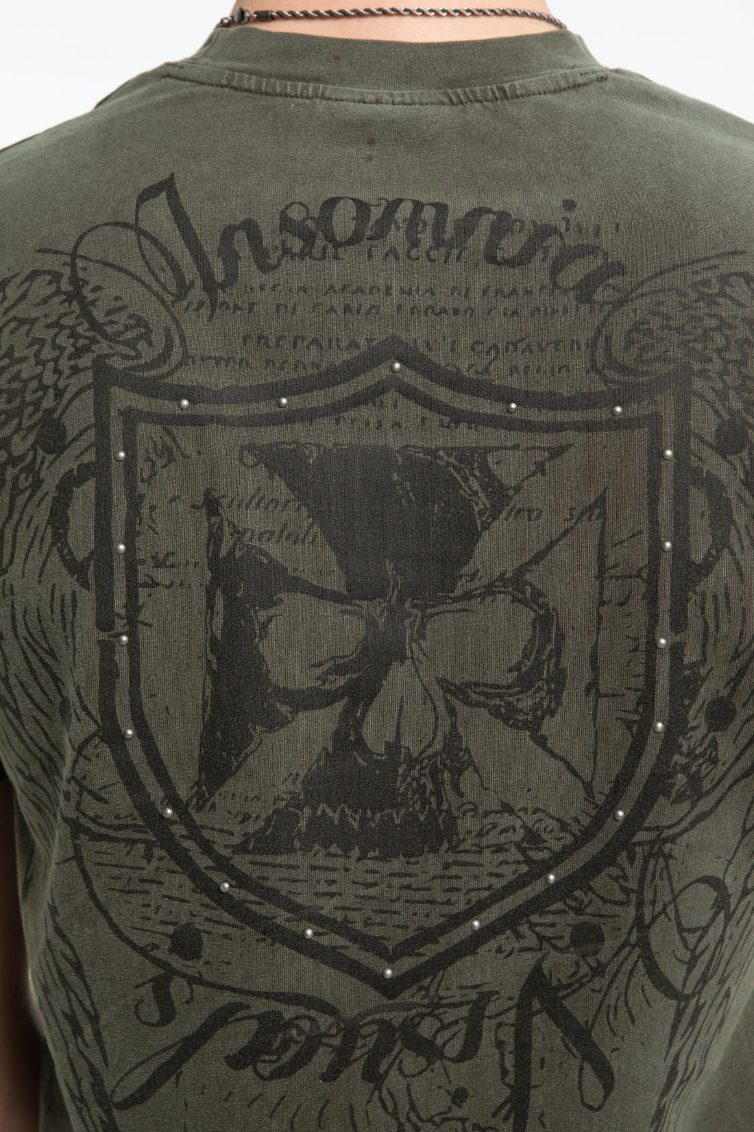 Close-up of the studded shield and cross crest on the back of the Studded Wings Tee