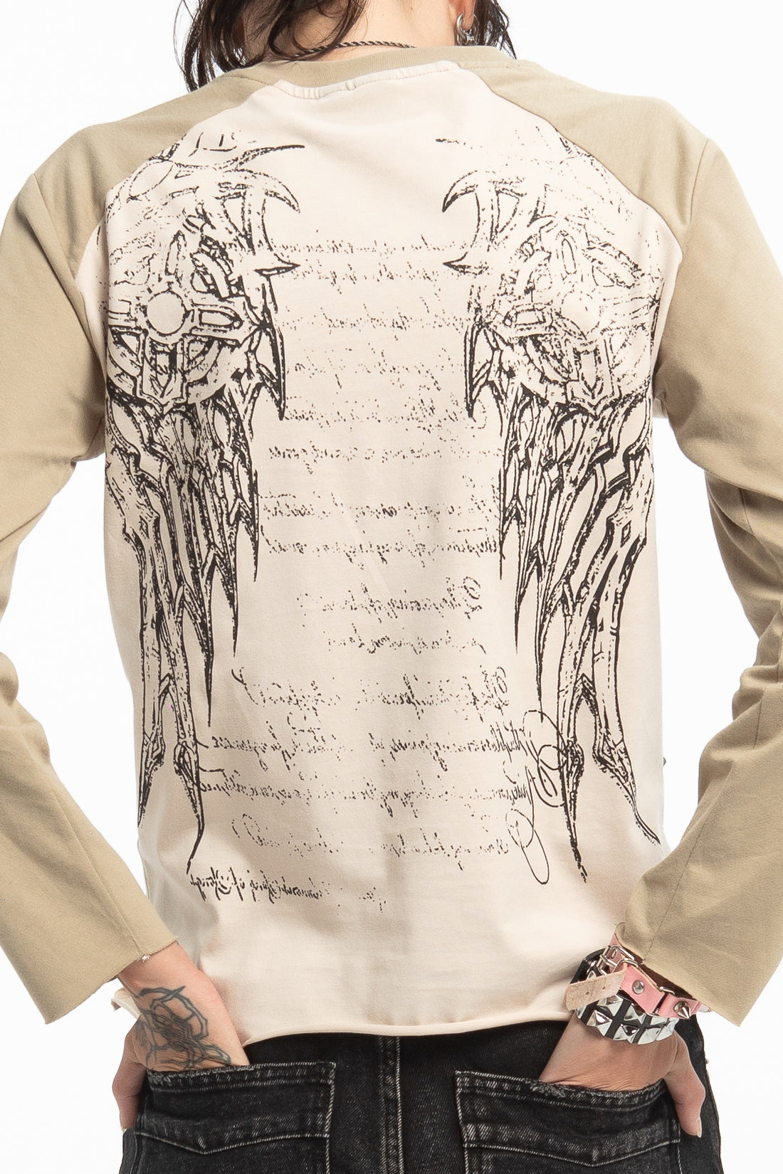 Close-up back view of the Reaper Raglan Long Sleeve's winged graphic worn with black jeans