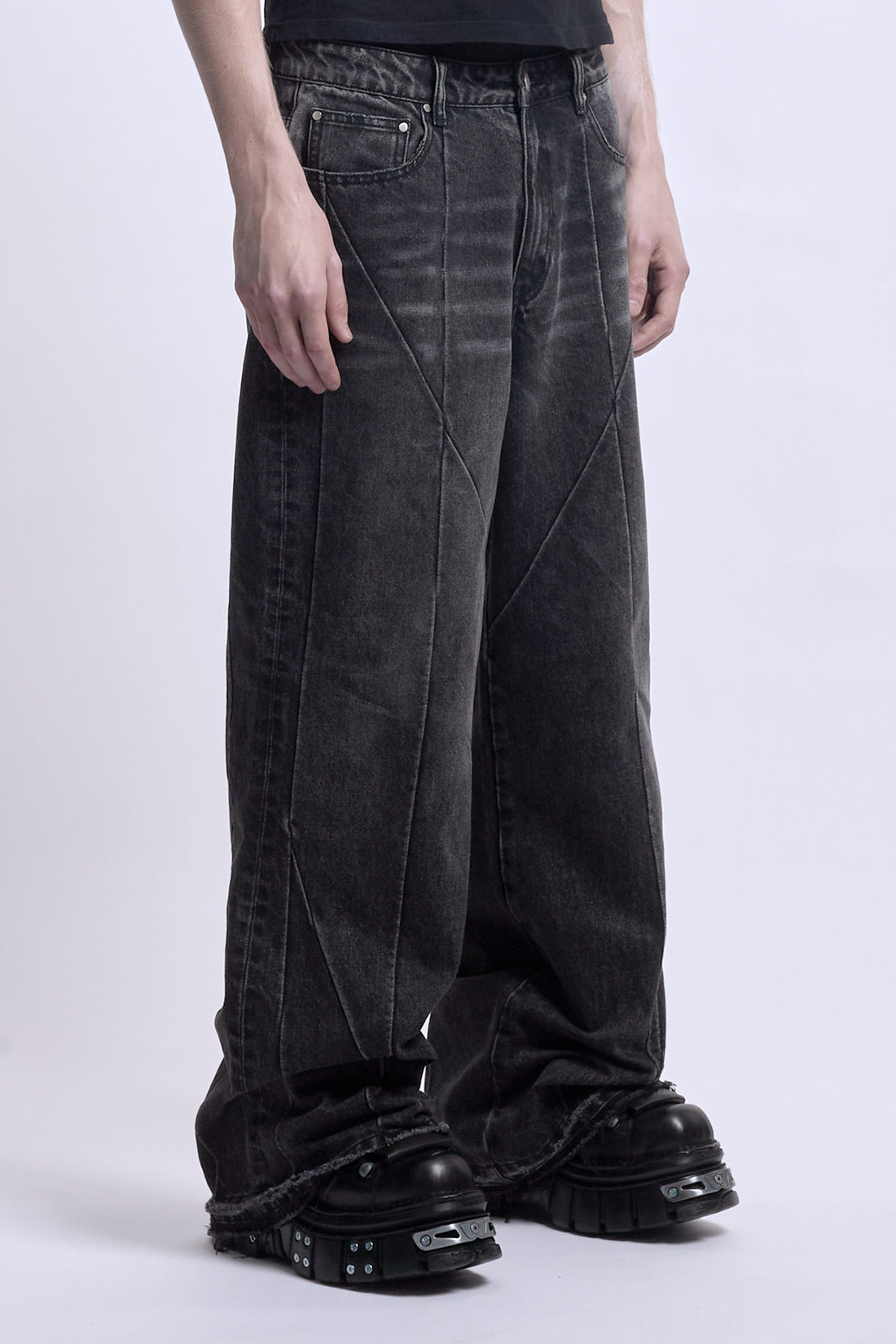 Side view from the waist down of the black Vex Denim with curved seam panels and frayed hems
