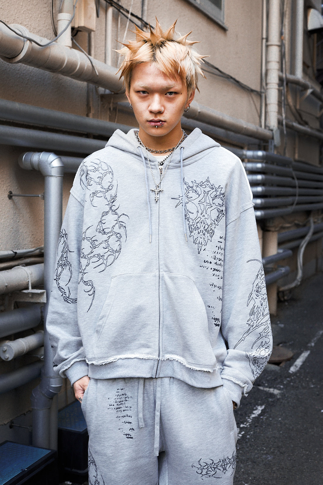 Model with spiky bleached hair in the Gray Sigil Zip Hoodie on a city street