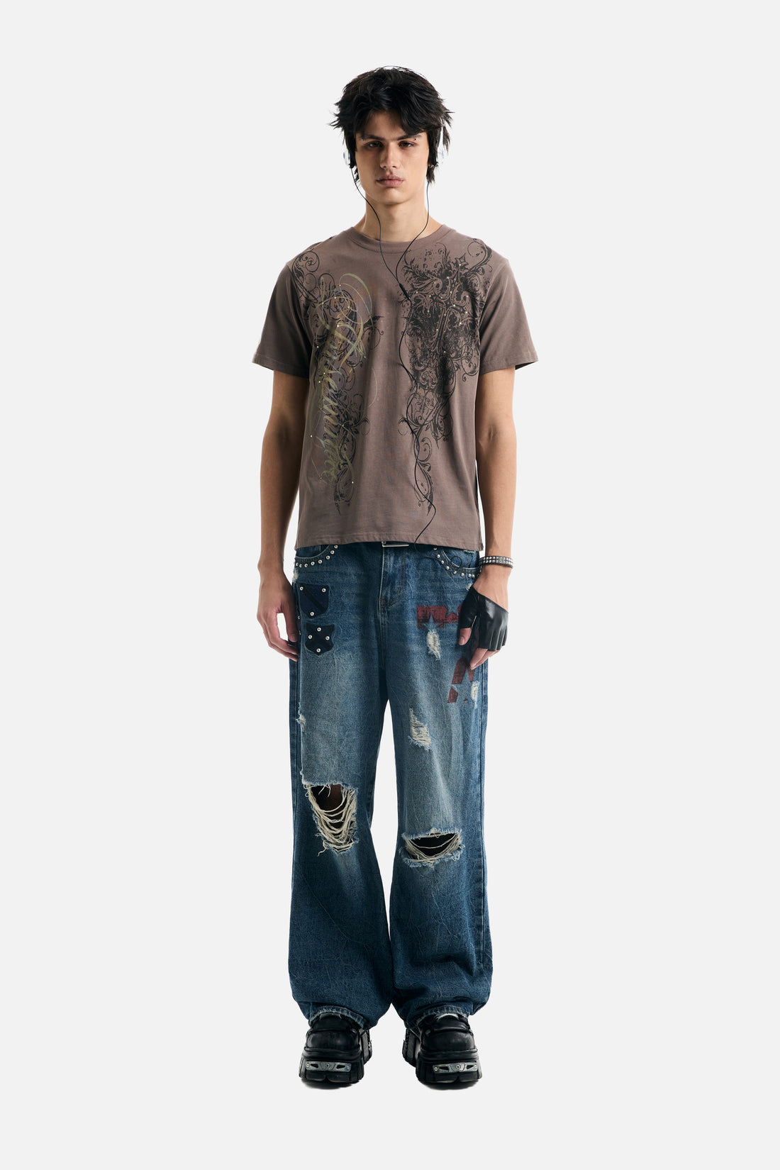 Full-length front view of the Brown Scripture Eclipse Tee with ripped studded jeans