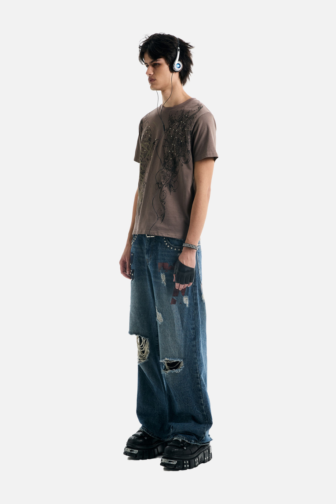 Full-length side view of the Brown Scripture Eclipse Tee with baggy distressed jeans and sneakers