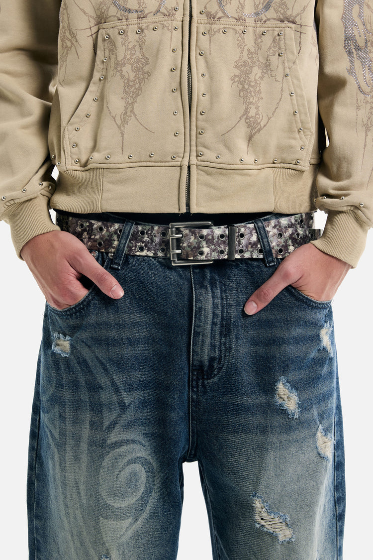 Camo Skull Belt worn with a tan studded zip hoodie and tribal-wash jeans, waist close-up